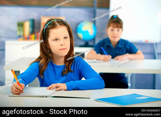 Schoolgirls sitting at desk in primary school classroom. Elementary age children