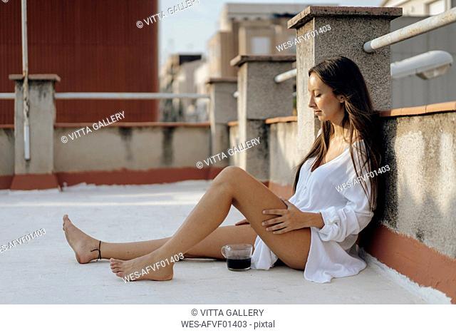 Young woman relaxing on roof terrace at sunset