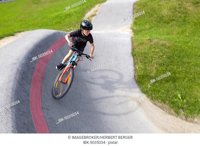 Child, boy, 11 years old, riding a mountain bike through a steep curve in a pump track, mountain bike trail, Viehhausen, Salzburg, Austria, Europe