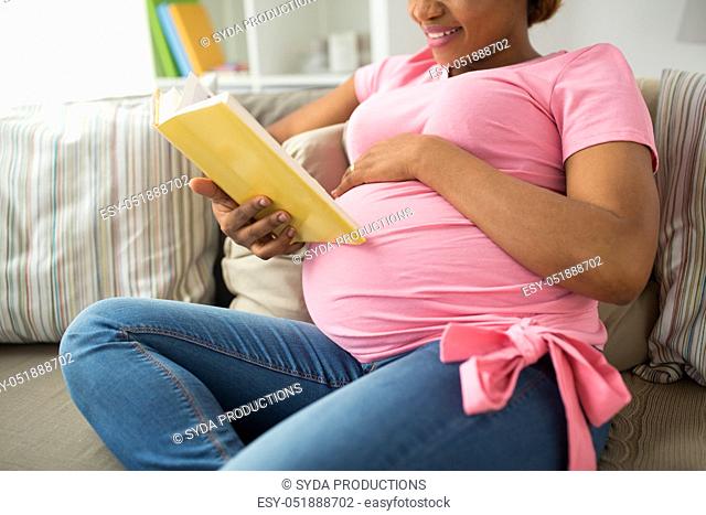 happy pregnant african woman reading book at home