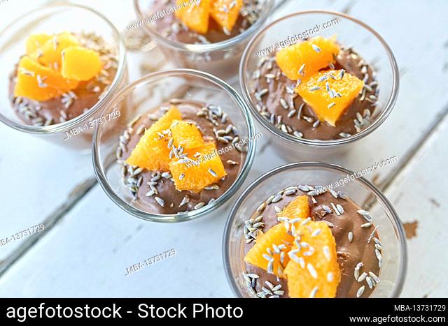 Ayurvedic cuisine - chocolate mousse with silken tofu, decorated with orange fillets and lavender flowers, filled small glass bowls stand on a white wooden...