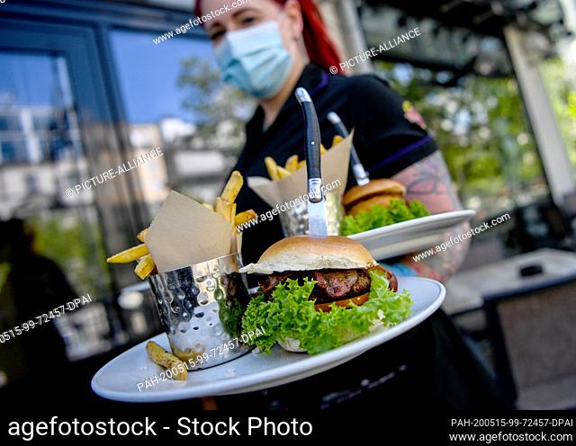 15 May 2020, Berlin: A waitress serves food at the Hard Rock Cafe Berlin. Restaurants with their own food offer are allowed to open their indoor and outdoor...