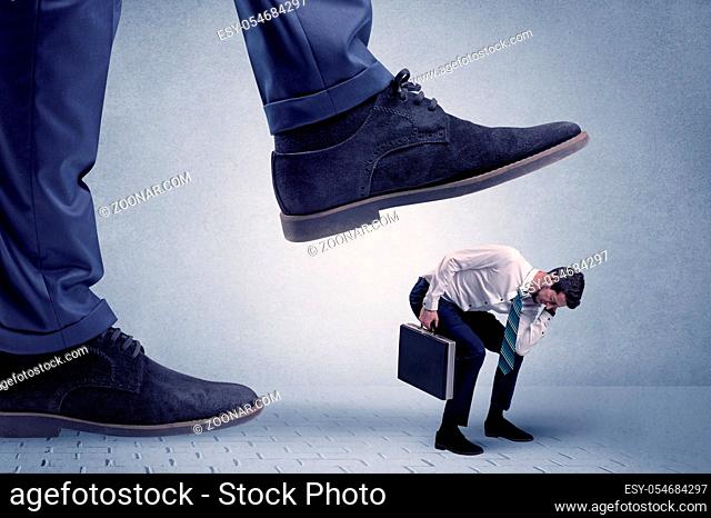 Young handsome businessman getting crushed by a big formal shoe