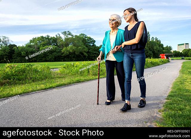 Smiling senior woman with mid-adult woman on footpath in park