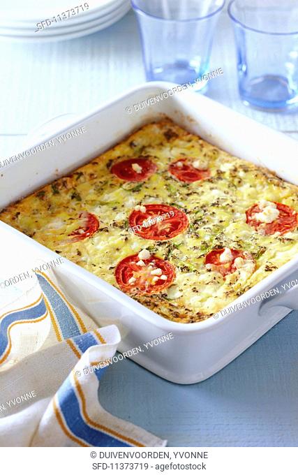 Oven-baked frittata with tomatoes, cheese, spring onions and herbs