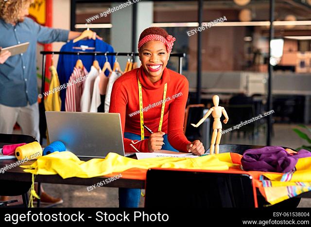Portrait of happy african american fashion designer at desk in studio office