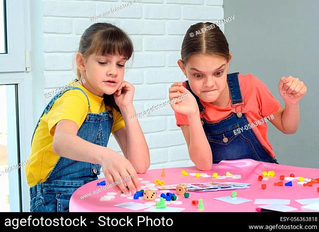 Girls play board games, one of them looks funny at the chips