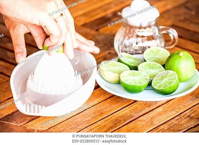 Hand squashing fresh lime on wood counter