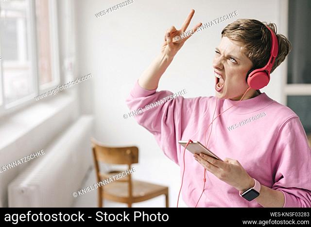 Woman with cell phone and headphones posing while listening to music