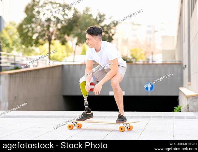 Smiling amputated man skateboarding against subway in city