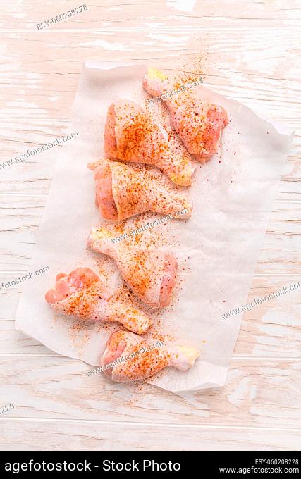 Raw chicken legs with seasoning on wooden kitchen table