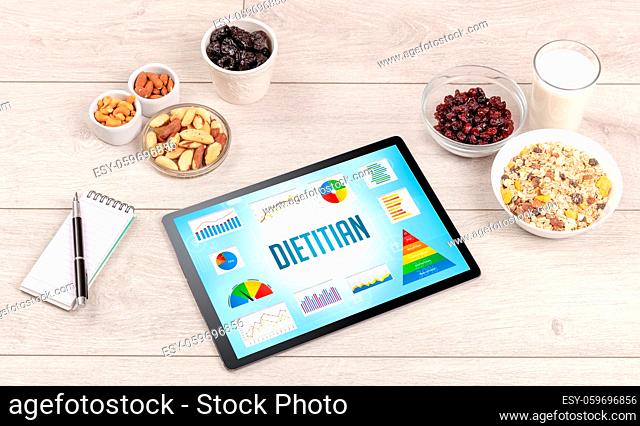 Organic food and tablet pc showing DIETITIAN inscription, healthy nutrition composition