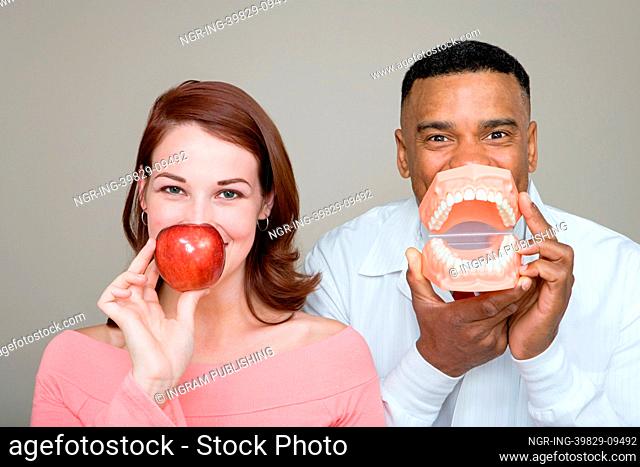 Dentist and woman holding an apple and false teeth
