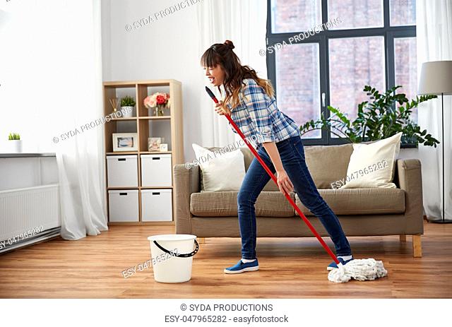 happy asian woman with mop cleaning floor at home