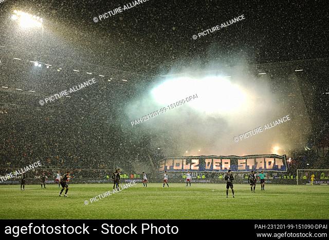 01 December 2023, Hamburg: Soccer: Bundesliga 2, FC St. Pauli - Hamburger SV, matchday 15 at the Millerntor Stadium. HSV fans set off pyrotechnics at the start...