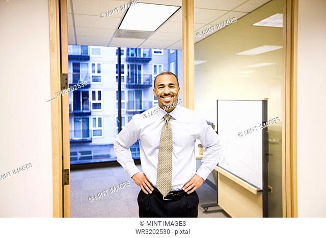 A portrait of a black businessman standing alone in his office space