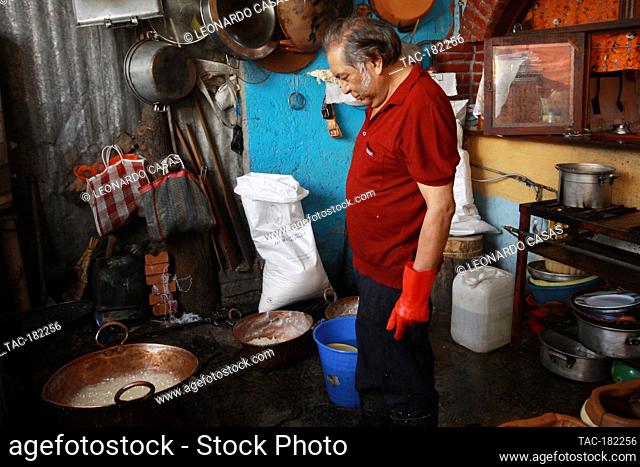 MEXICO CITY, MEXICO - OCTOBER 23: A person cooks a mixture of sugar with water into a clay mold in the shape of a skull during the making of the traditional...