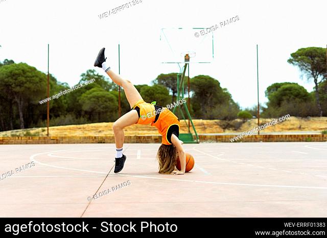 Teenage girl doing acrobatics on basketball ground