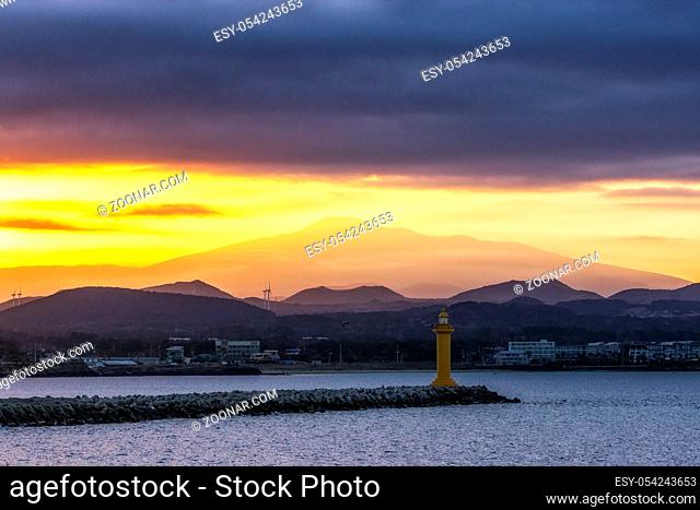 The view of Mount Hallasan with seongsan harbor light house taken from a ferry during sunset hours. Jeju Island, South Korea