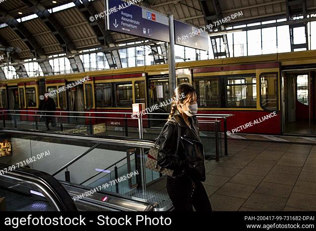 17 April 2020, Berlin: A woman wearing a mouth guard walks across a platform at Alexanderplatz station. Due to closures due to construction work