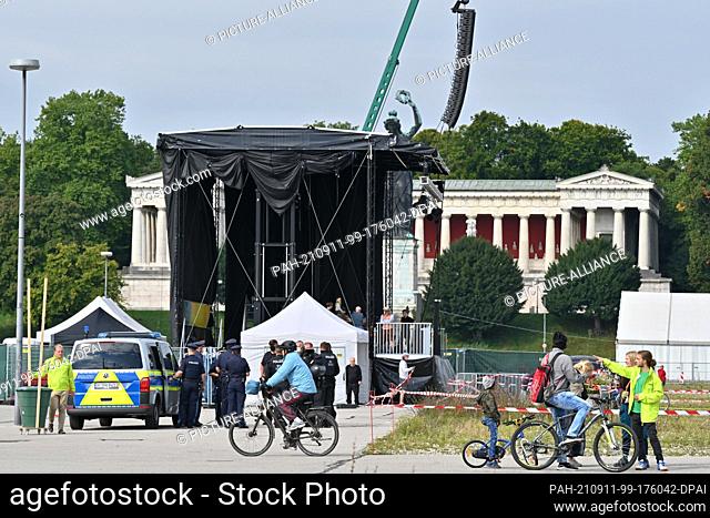 13 March 2020, Bavaria, Munich: Cyclists ride across the Theresienwiese while police officers stand in front of the stage in the background