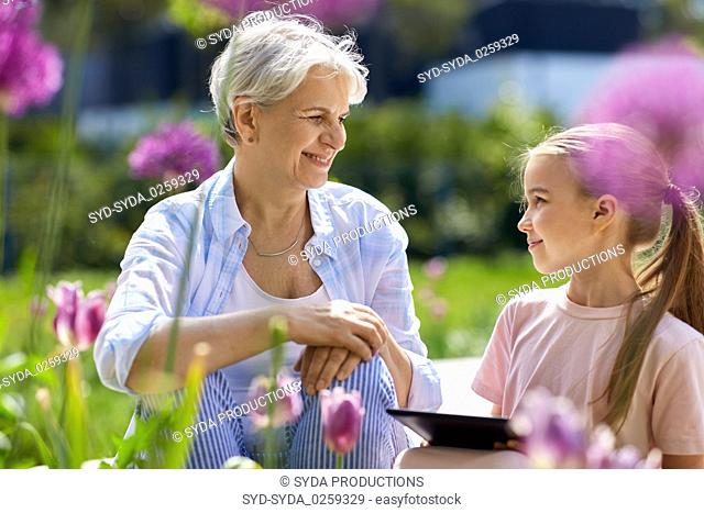 grandmother and girl with tablet pc at garden