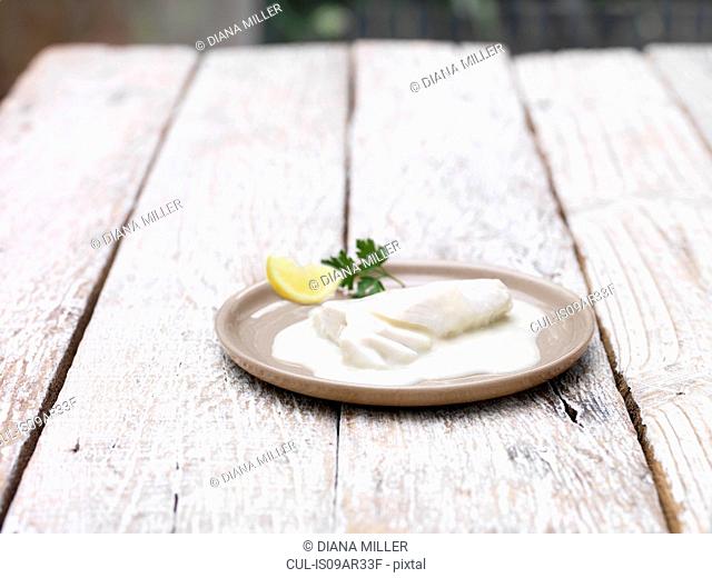 Plate of bake in bag haddock mornay on wooden table