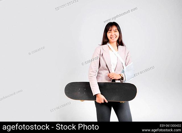 Woman smile broken arm after accident wear arm splint for treatment she play skateboard skating accident sport extreme, happy Asian female sling support hand...