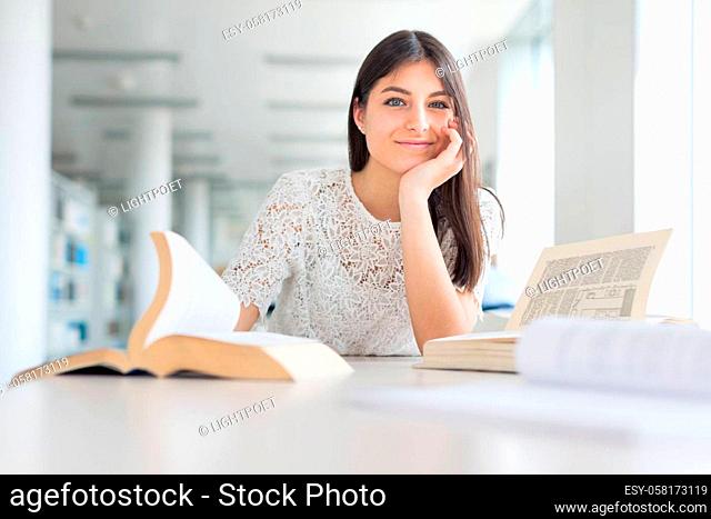 Pretty, young college student looking for a book in the library, studying for her exam