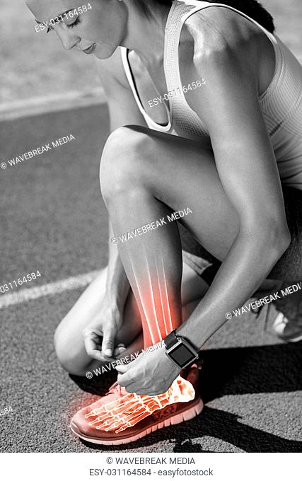 Highlighted bones of woman tying shoe lace on race track