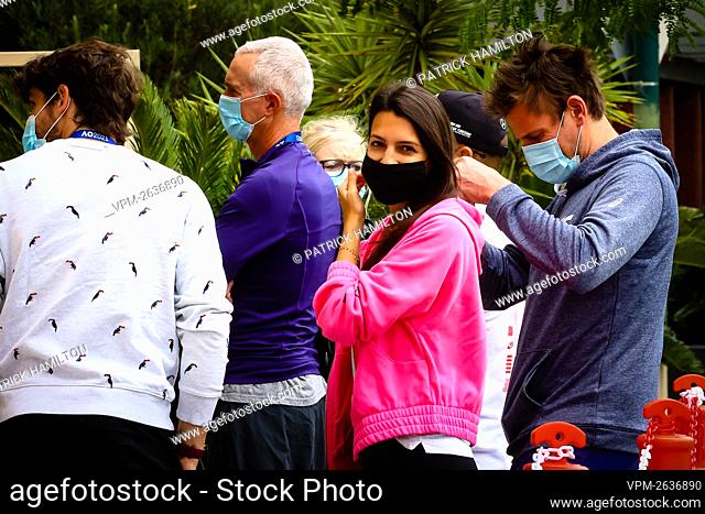 (L-R) Goffin's coach Germain Gigounon, Goffin's wife Stephanie Tuccitto, Goffin's physical coach Fabien Bertrand wait in a queue at the test center at the View...