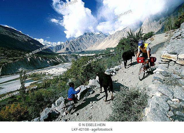 Mountain biker und shepherd boy in the mountains, Karakorum Highway, Hunza Valley, Pakistan