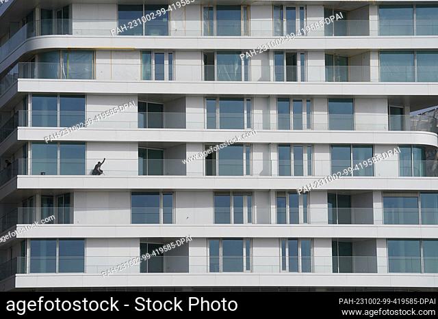 02 October 2023, Hamburg: A window cleaner cleans the glass facades and glass balconies of a new building in Hafencity. Photo: Marcus Brandt/dpa