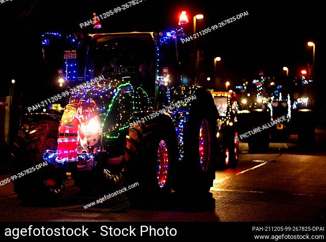 05 December 2021, Bremen: Christmas-decorated tractors drive through a street in the Horn-Lehe district at the start of a light drive