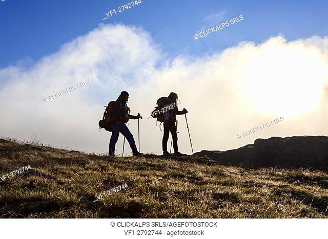 Hikers admire the landscape at dawn Minor Valley High Valtellina Livigno Lombardy Italy Europe