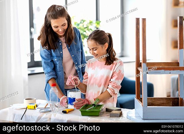 mother and daughter stirring grey paint at home