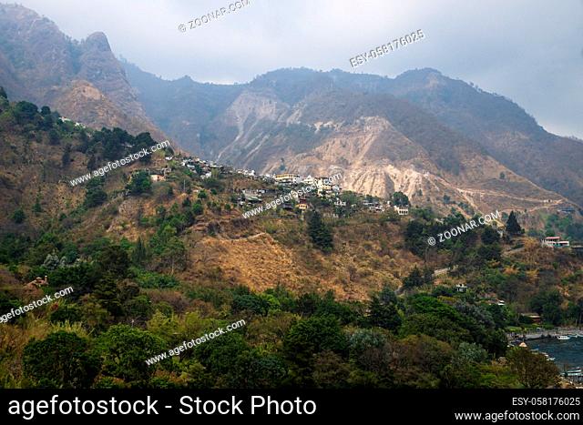 View up to steep green misty mountain with the village of Santa Cruz la Laguna, Guatemala