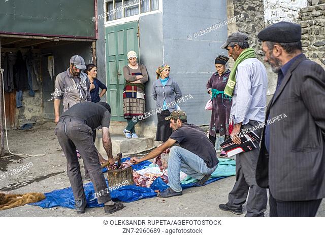 Men butcher a bull in a yard in Khinalig village, Quba region, Azerbaijan. Khinalig is an ancient village located deep in Caucasian mountains on the height of...