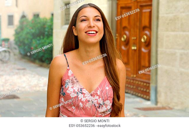 Portrait of cheerful fashion woman walking in street of old town in Italy