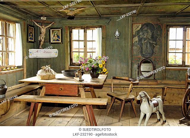 View inside the farmhouse with wooden bench, table and rocking horse, South Tyrolean local history museum at Dietenheim, Puster Valley, South Tyrol, Italy