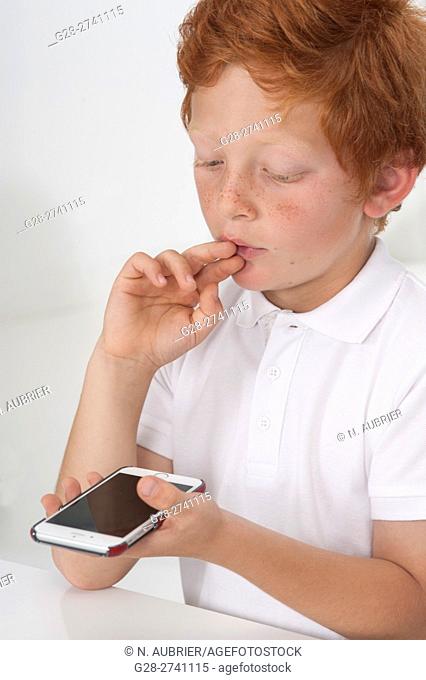 Small boy holding an i phone and looking puzzled