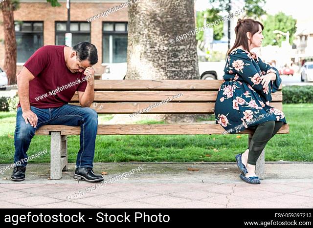 Unhappy Mixed Race Couple Sitting Facing Away From Each Other on Park Bench