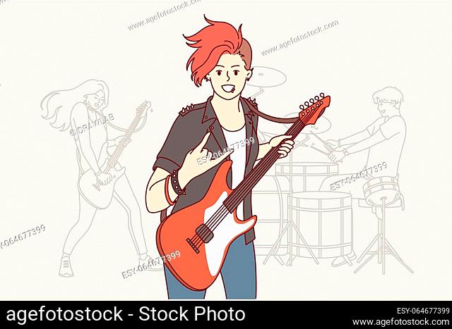 Girl rock musician plays guitar and makes gesture of goat enjoying performance at heavy music concert. Woman participating in rock band performing in nightclub...