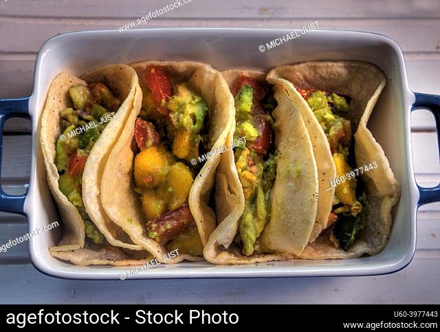 Top view of tacos with mango, avocado, jalapeno, tomato and red onion