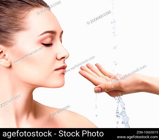 Beautiful woman face and splashes of water in hands. Cleansing and moisturizing concept