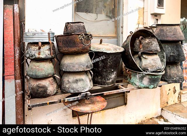 Several old cauldrons in heap in front of a facade
