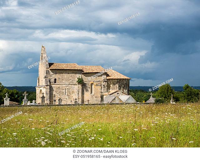 Church of Meillac Gours with sunlight and dark thunderstorm clouds