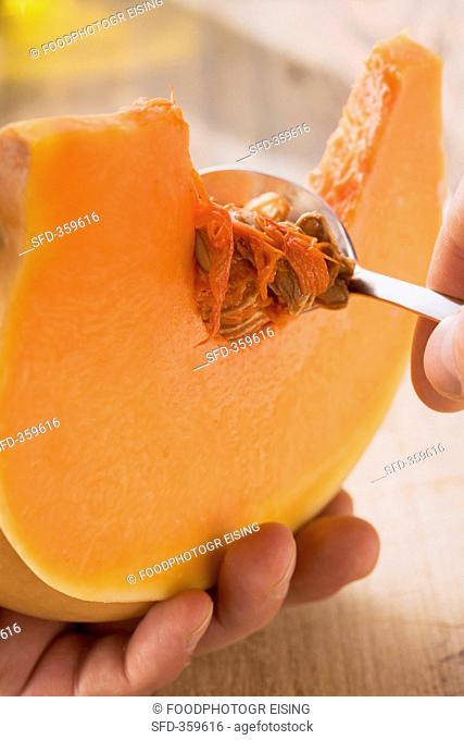 A slice of pumpkin being de-seeded