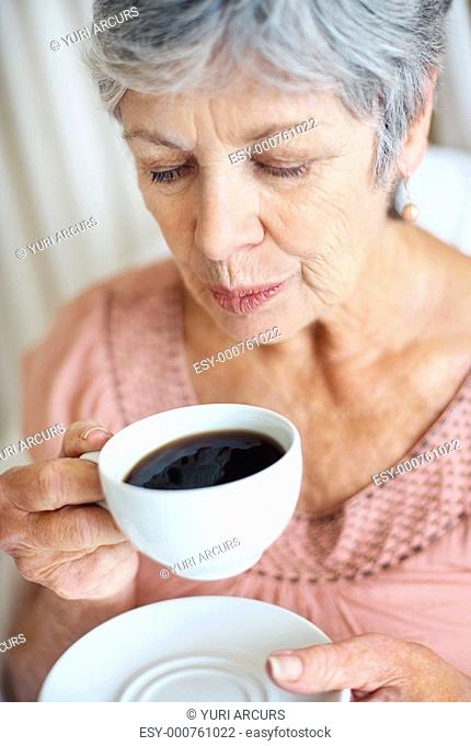 Closeup of a senior woman blowing cool air in her cup of tea