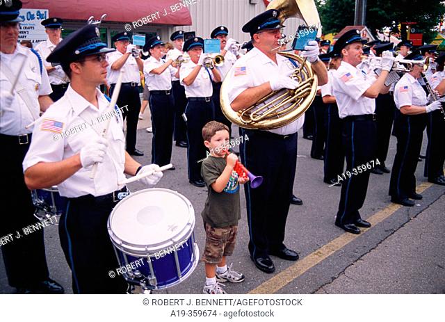 Young boy marches with band playing toy trumpet. Delaware state fair. USA